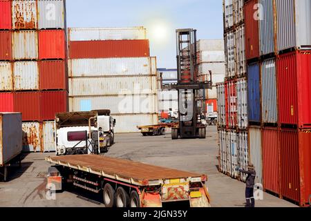 container forklift and load the containers on the truck trailer in the port against the background of the containers. Stock Photo