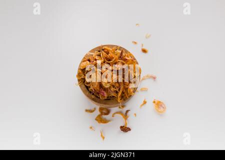 Fried shallot or bawang goreng in wooden bowl isolated on white background Stock Photo