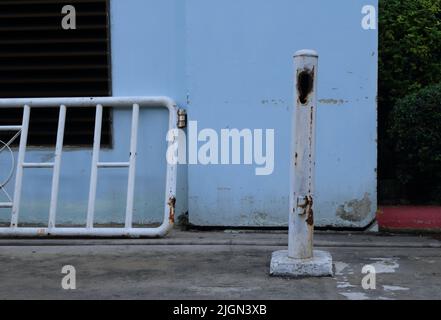 Closeup of damaged fence post standing on cement base, the post leans to the right Stock Photo