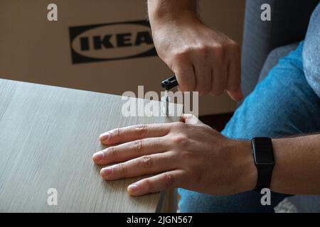 Vilnius, Lithuania - July 7, 2022: Man hands assembling Ikea furniture using screw allen. IKEA is Swedish-founded, world's largest furniture retailer Stock Photo