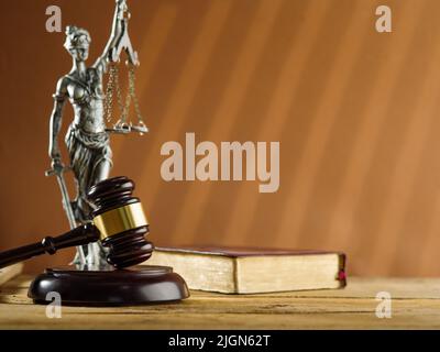 Bronze figurine of Themis - the goddess of justice, a book of the Constitution and a wooden gavel of a judge on a beige background. Symbols of a fair Stock Photo