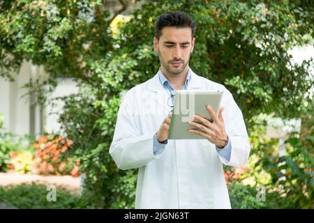Portrait of a man in lab coat using a digital tablet standing in a greenhouse Stock Photo