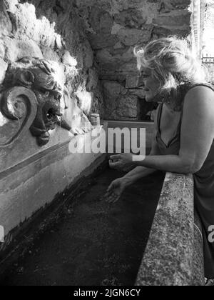 Woman watering and washing on a public foutain in Castell'Arquato Italy.Pure and precious to nature. Shot of hands held out to catch a stream of water Stock Photo
