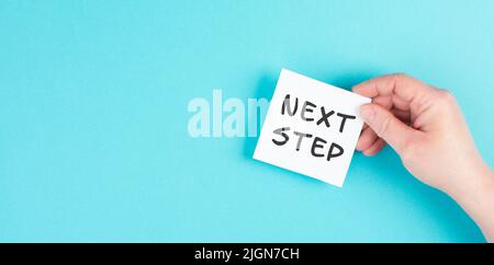 he phrase next step is standing on a paper, having new goals and strategies, making plans for future Stock Photo