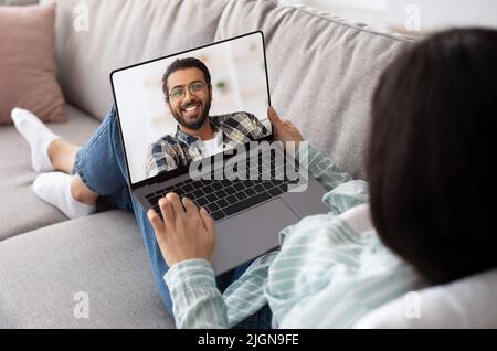 Woman using laptop at home for video chat with her indian boyfriend Stock Photo