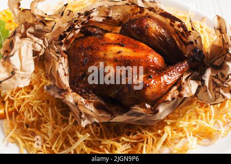Baked chicken served in paper with fried potato Stock Photo
