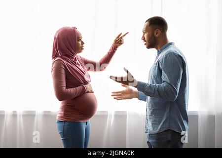 Relationship Problems During Pregnancy. Pregnant Black Muslim Couple Arguing At Home Stock Photo