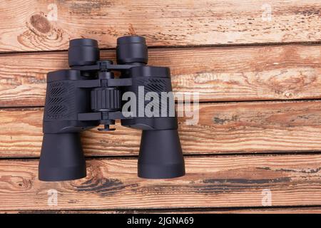 Black binoculars on a wooden surface Stock Photo