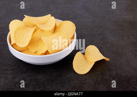 Potato chips on a stone black surface in a saucer Stock Photo