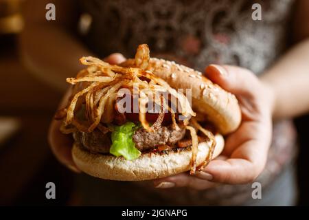 Tasty hamburger with onions in female hands Stock Photo