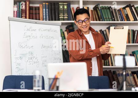 Korean Teacher Having Online Class Showing Flipboard To Laptop Indoors Stock Photo