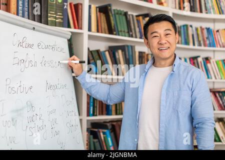 Joyful Asian Teacher Man Near Whiteboard Standing In Classroom Stock Photo