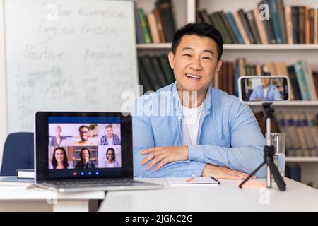 Asian Male Teacher Video Calling Talking With Students At Workplace Stock Photo
