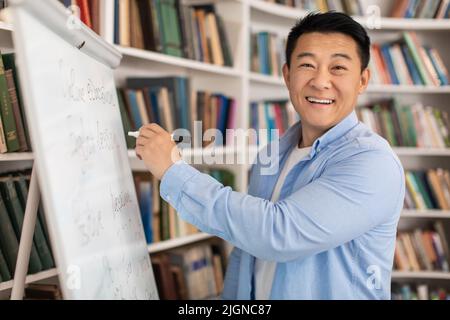 Cheerful Japanese Tutor Man Writing On Whiteboard Having Lesson Indoor Stock Photo