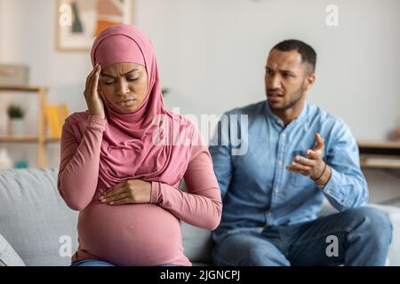 Black Pregnant Muslim Woman Feeling Unwell While Arguing With Husband At Home Stock Photo