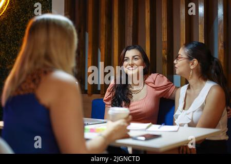 Students sitting talking at cafe as friends Stock Photo