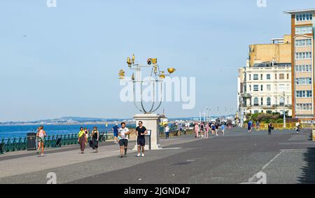 Hove , Brighton UK 12th July 2022 - Runners and walkers  are out early along Hove seafront by the plinth as the hot sunny weather continues throughout Britain with temperatures expected top reach over 30 degrees in some parts  : Credit Simon Dack / Alamy Live News Stock Photo