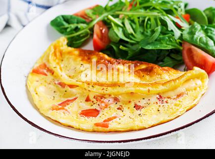 Omelette with tomatoes and salad on white plate.  Frittata - italian omelet. Stock Photo