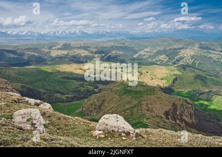 Atmospheric alpine landscape with mountain range and green hills under dramatic cloudy sky. Beautiful highland scenery. Stock Photo