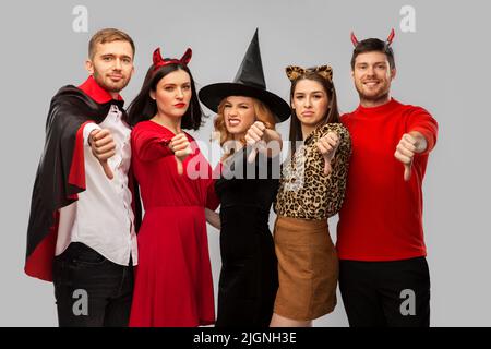 friends in halloween costumes snow thumbs down Stock Photo