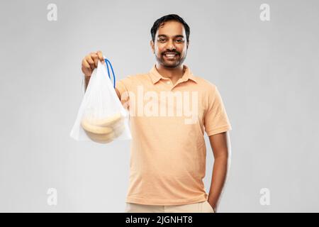 happy man holding reusable string bag with bananas Stock Photo