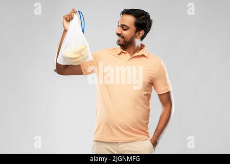 happy man holding reusable string bag with bananas Stock Photo