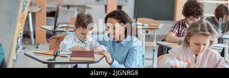 Happy kind teacher is helping kids in elementary school lessons Stock Photo