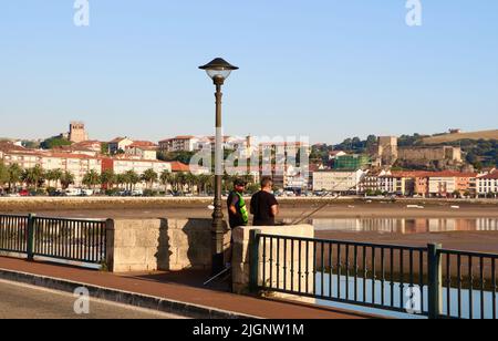 Men rod and line fishing from the Maza road bridge in the Spanish town San Vicente de la Barquera Cantabria Spain Stock Photo