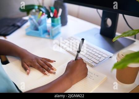 A woman writes in her journal at her neat desk Stock Photo