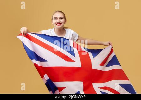 attractive blonde poses with a British flag. photo shoot in the studio on a yellow background. Stock Photo