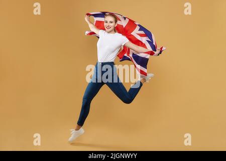 attractive blonde made a jump with a British flag. photo shoot in the studio with a yellow background. Stock Photo
