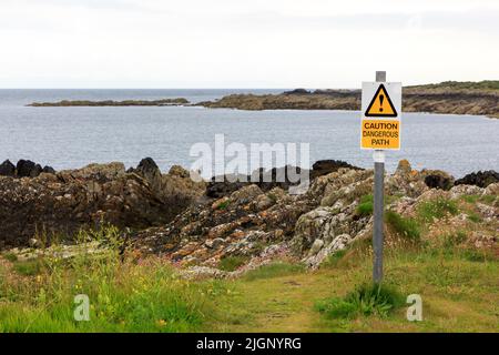 Dangerous Path caution sign close to a rocky outcrop Stock Photo