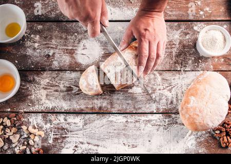 Cutting homemade bread on kitchen table flat lay Stock Photo