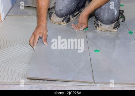Installing ceramic tiles on an adhesive surface while working on the construction Stock Photo
