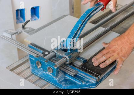 In construction worker cutting is using manual tools equipment to lay ceramic tiles on the floor Stock Photo