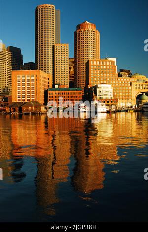 The skyline of the Boston Financial District in downtown is sen reflecting in the waters of the harbor on a still and tranquil day Stock Photo