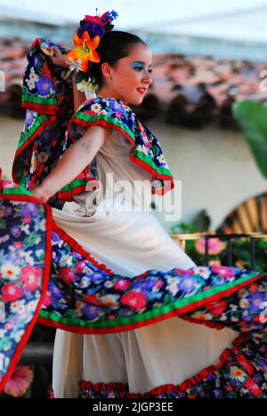 A young woman wearing a traditional dress participates in a show and performance highlighting the dance culture of Mexico and Mexican music Stock Photo