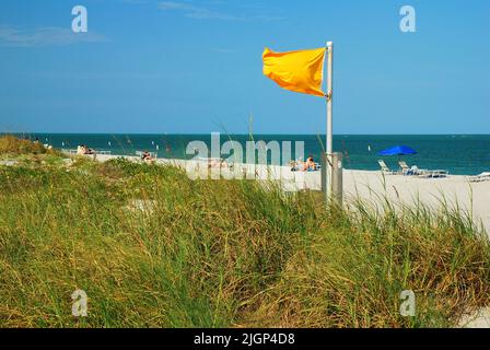 A yellow flag waves at the shore near Miami Florida to warn beach travelers about potentially dangerous surf and ocean conditions Stock Photo