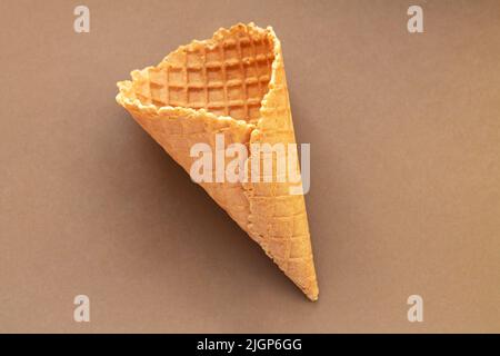 Single empty wafer ice cream cone on brown table. Top view Stock Photo