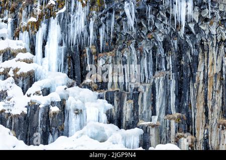 Icicles formed from the spray from Svartifoss, Iceland. A thin, 20m waterfall down the center of a dramatic 3D wall of hexagonal basalt columns. Stock Photo
