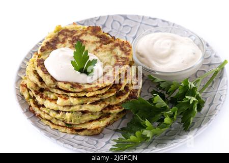 Zucchini fritters with yogurt sauce isolated on white background Stock Photo