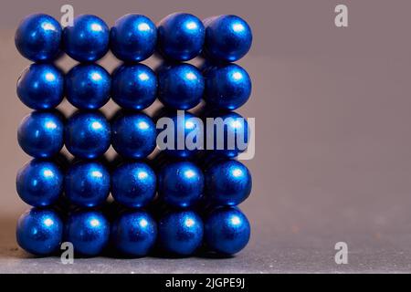 Magnetic cube made of blue metal balls on a colored background Stock Photo