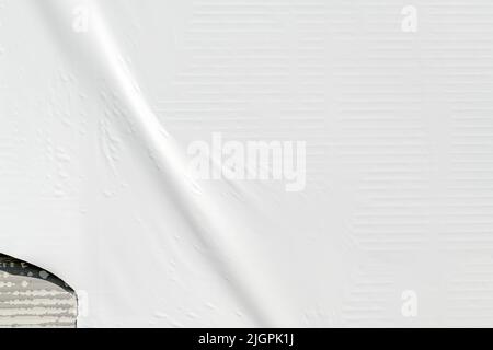 Crumpled white advertising poster paper glued on the wall as copy space and background. Graphic design element. Stock Photo