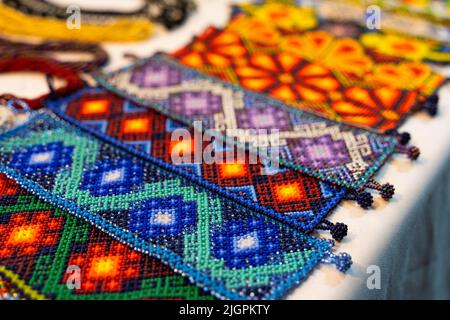 Colorful huichol bracelets at night market in Guadalajara, Mexico. Traditional Mexican handcraft souvenirs Stock Photo