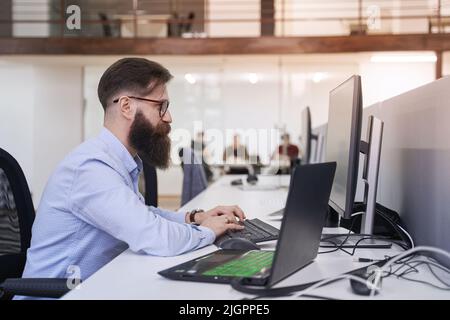 Senior computer programmer developer working in IT office, sitting at desk and coding, working on a project in software development company or startup Stock Photo