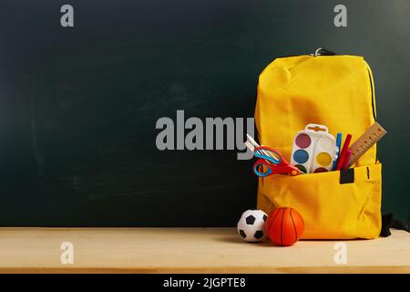 School backpack with colorful school supplies on table. Stock Photo