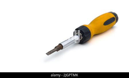 Yellow metallic manual multi-bit screwdriver with replaceable bits. Close-up photo of repair work tool isolated on a white background. Selective focus on a single object. Stock Photo