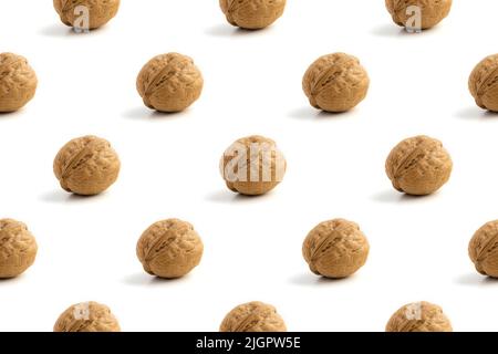 Seamless pattern with ripe whole walnuts on a white background with hard light and shadow. Healthy lifestyle concept and vegetarianism. Close-up photo Stock Photo