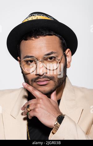 portrait of eastern hip hop performer in fedora hat and eyeglasses isolated on grey Stock Photo