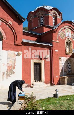 A female monk in black habit ironing some clothes outside the medieval Serbian Orthodox  'Patriarchate of Peć' Monastery in Kosovo. Stock Photo